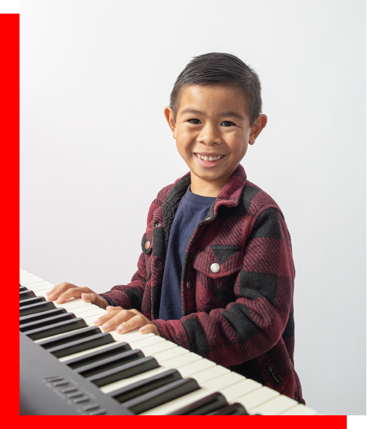 Smiling child playing keyboard during piano lessons for kids in Duarte, California, focused on foundational music skills